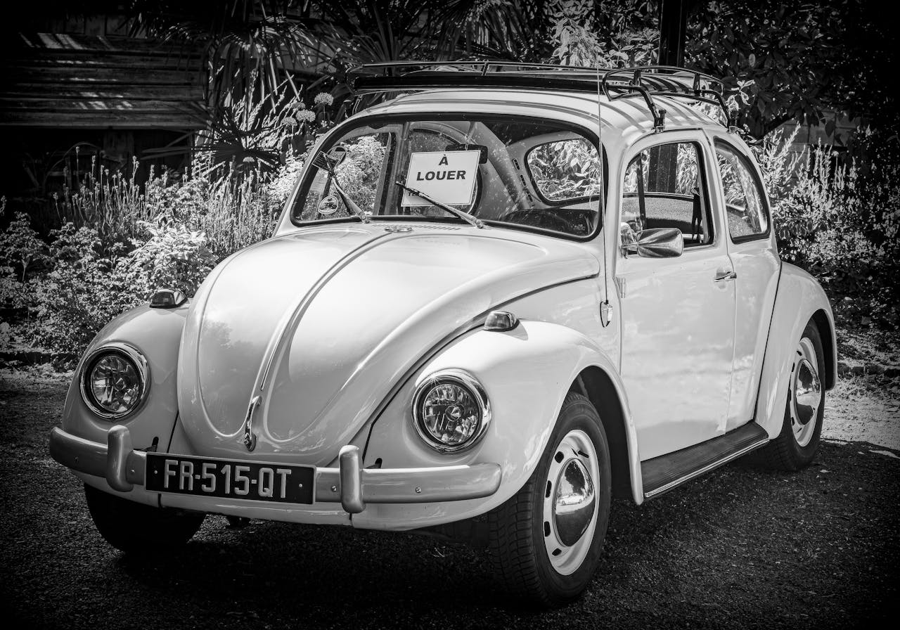Classic white car with 'For Rent' sign in a rustic outdoor setting.